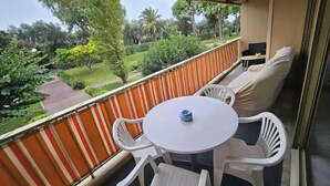 A balcony with a striped orange and white barrier, white plastic chairs, a small round table, and a sofa. - Luxurious Vintage 3 Rooms (Antibes)