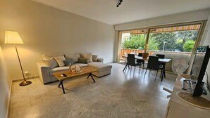 A modern living room with a sofa, coffee table, and dining area. - Luxurious Vintage 3 Rooms (Antibes)