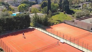 A tennis court with a net, surrounded by trees and buildings. - Luxurious Vintage 3 Rooms (Antibes)