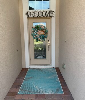 Welcome to a charming entrance with a welcoming sign and decorative wreath.