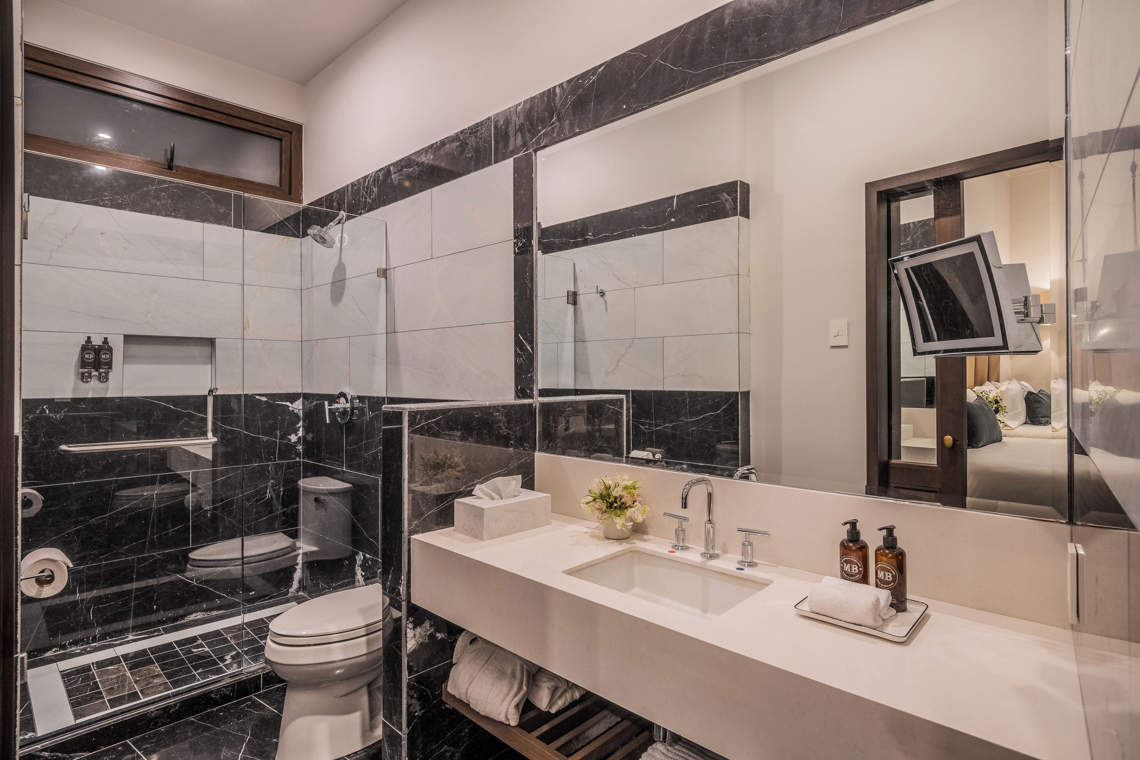 Un baño moderno con cabina de ducha de vidrio, un lavamanos blanco con espejo y un inodoro.