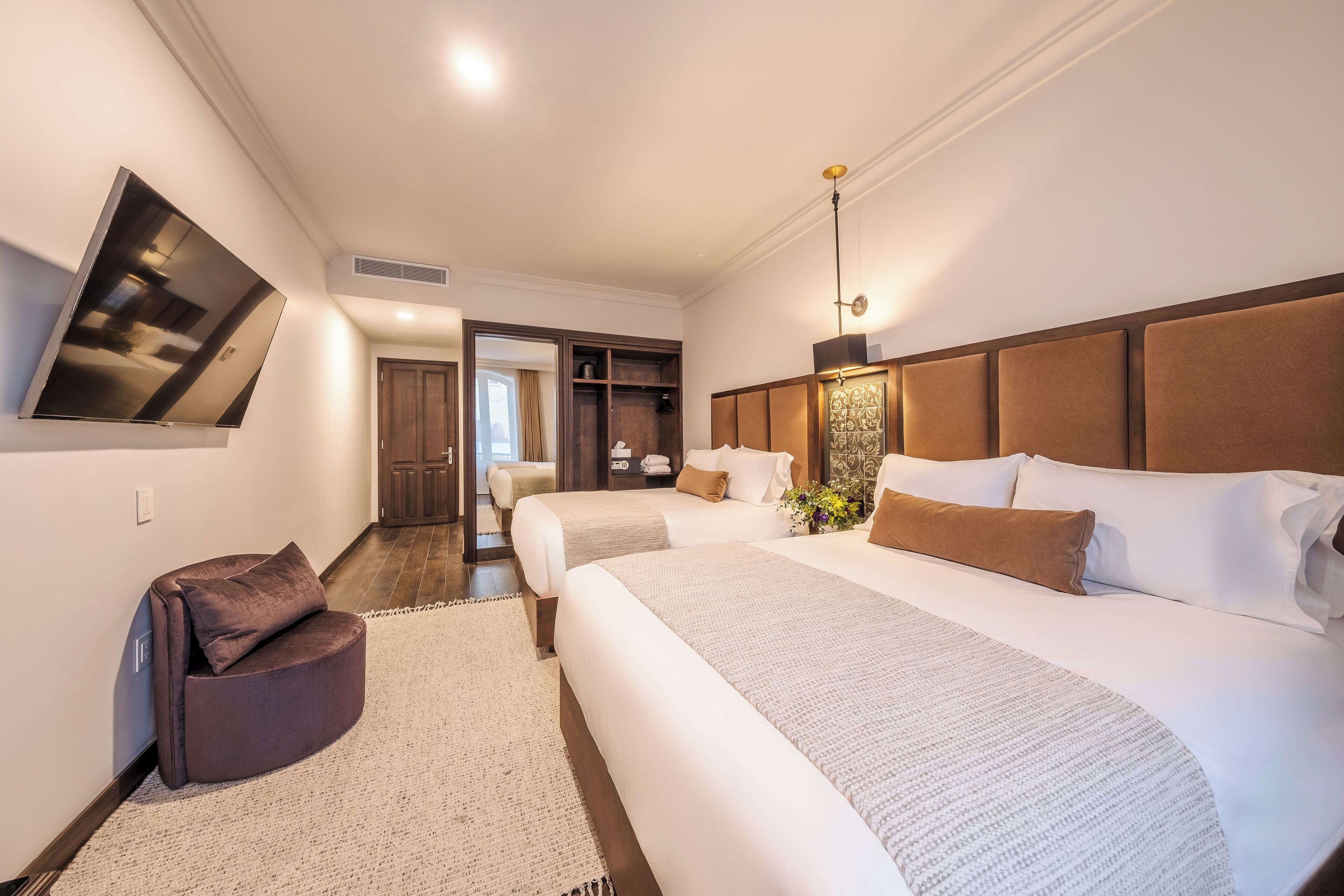Una habitación de hotel moderna con una cama grande, un sofá, un televisor y un vestidor.