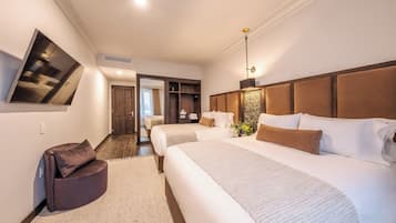 Una habitación de hotel moderna con una cama grande, un sofá, un televisor y un vestidor.