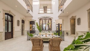 A spacious indoor area with a high ceiling, a central dining table set for four, and two wicker chairs. - Casa Kloster Hotel Boutique (Guanajuato)