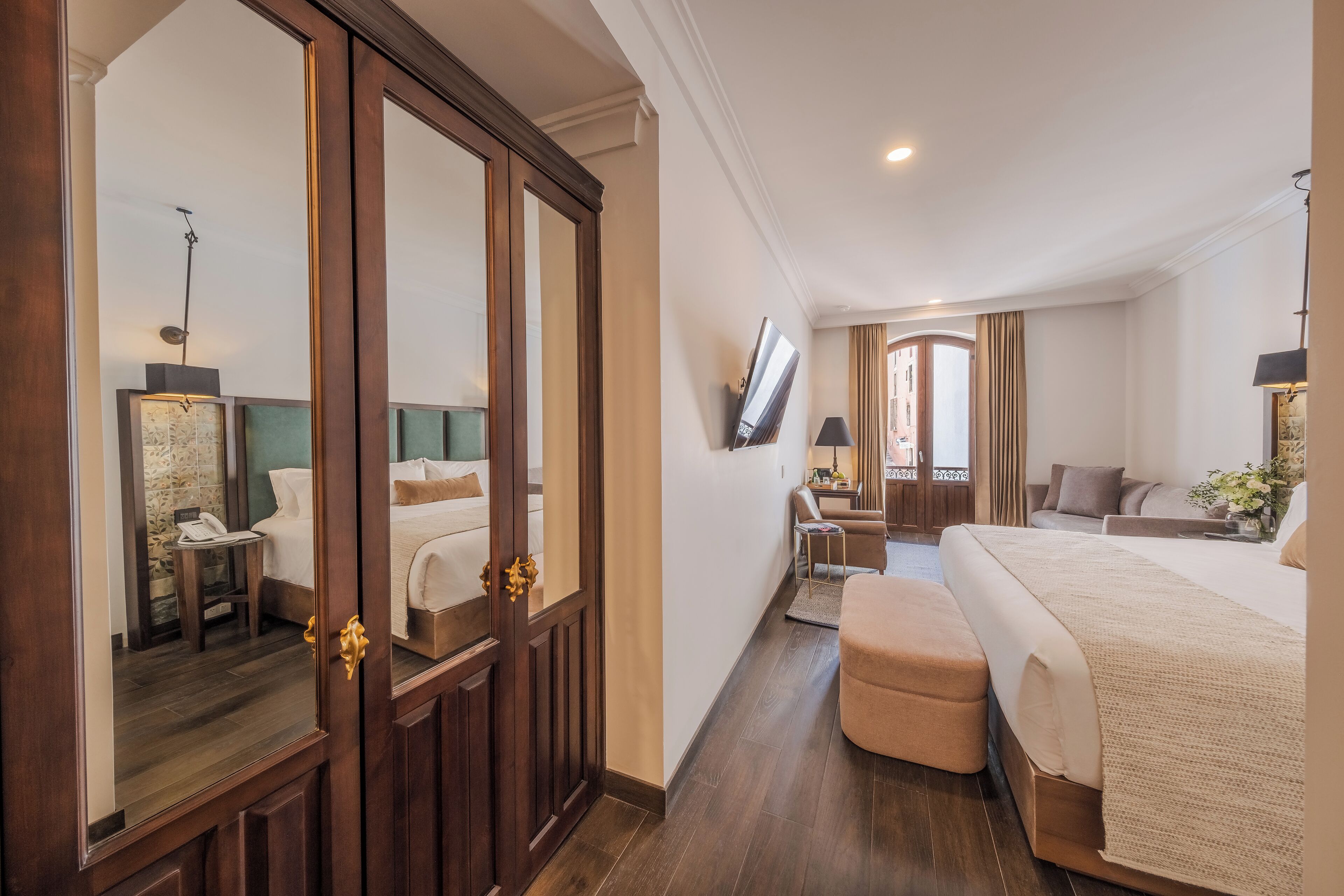 A hotel room with a large bed, a desk, a chair, a TV, and a mirror.