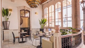 A sunlit interior with a dining area, potted plants, and a view through large windows. - Casa Kloster Hotel Boutique (Guanajuato)