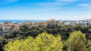 Zona residencial a la costa, amb edificis, un cel blau clar i vista al mar.