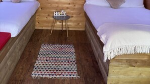 A cozy room with wooden walls, two beds, a small table, and decorative items. - The Hideaway Muff - Private estate, Shebeen, Lough Foyle (Muff)