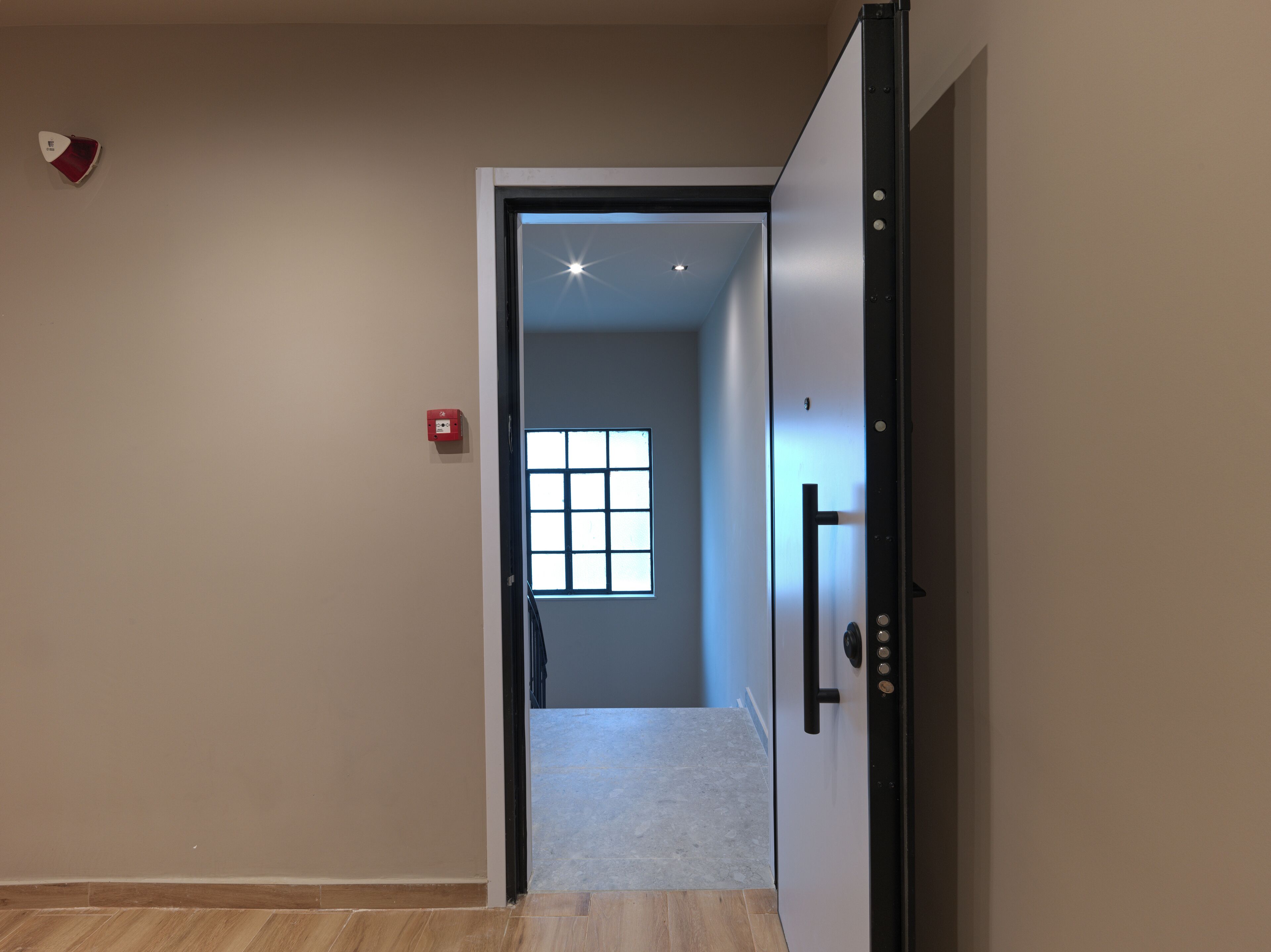 A hallway with a door leading to a room with a window.