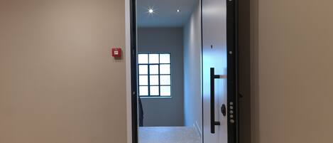A hallway with a door leading to a room with a window.