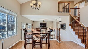 A spacious dining area with a high ceiling, a chandelier, and a view through large windows.