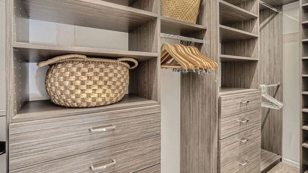 A walk-in closet with multiple shelves, drawers, and a hanging rod.