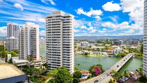Un hotel de gran altura con varios pisos, vista a un río y un puente al fondo.