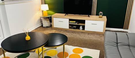 A modern living room with a black and white TV stand, a grey sofa, and a polka dot area rug.