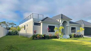 Una casa moderna de dos pisos con techo plano, ventanas amplias y un césped bien cuidado.