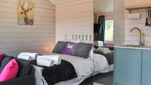 Een slaapkamer met een bed, kussens, een spiegel, een wastafel en een schilderij aan de muur.