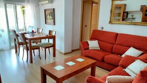 Una sala de estar con un sofá rojo, una mesa de centro de madera y un comedor con una mesa y sillas de madera.