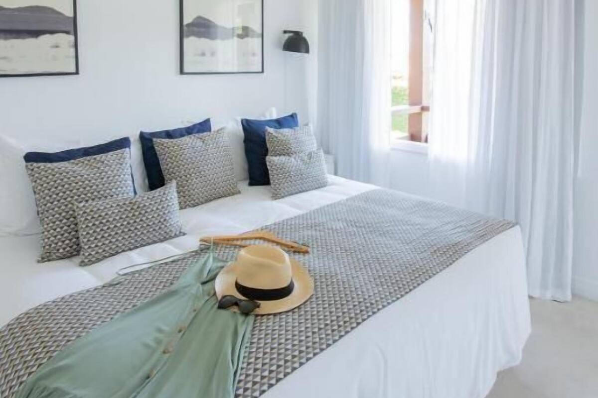 Un dormitorio con una cama grande, paredes blancas y una ventana con cortinas.