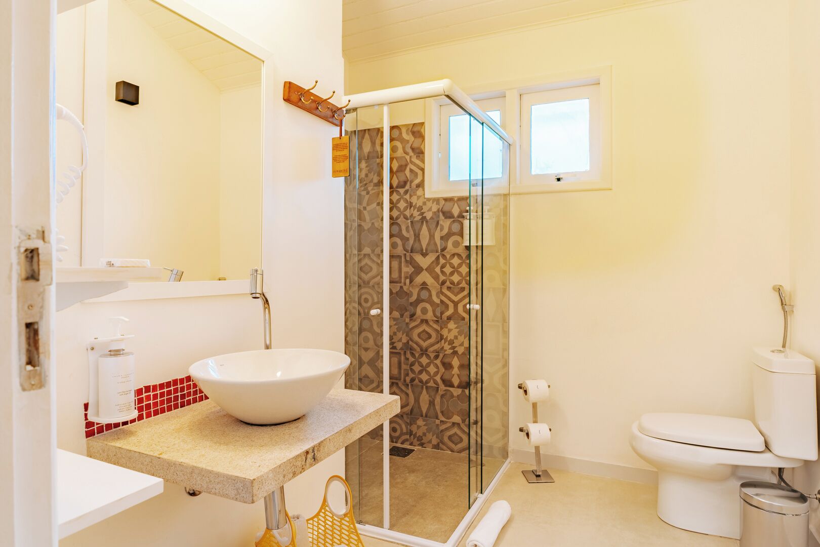 Un baño moderno con un lavamanos grande de color blanco, una cabina de ducha con paredes de vidrio y un inodoro.