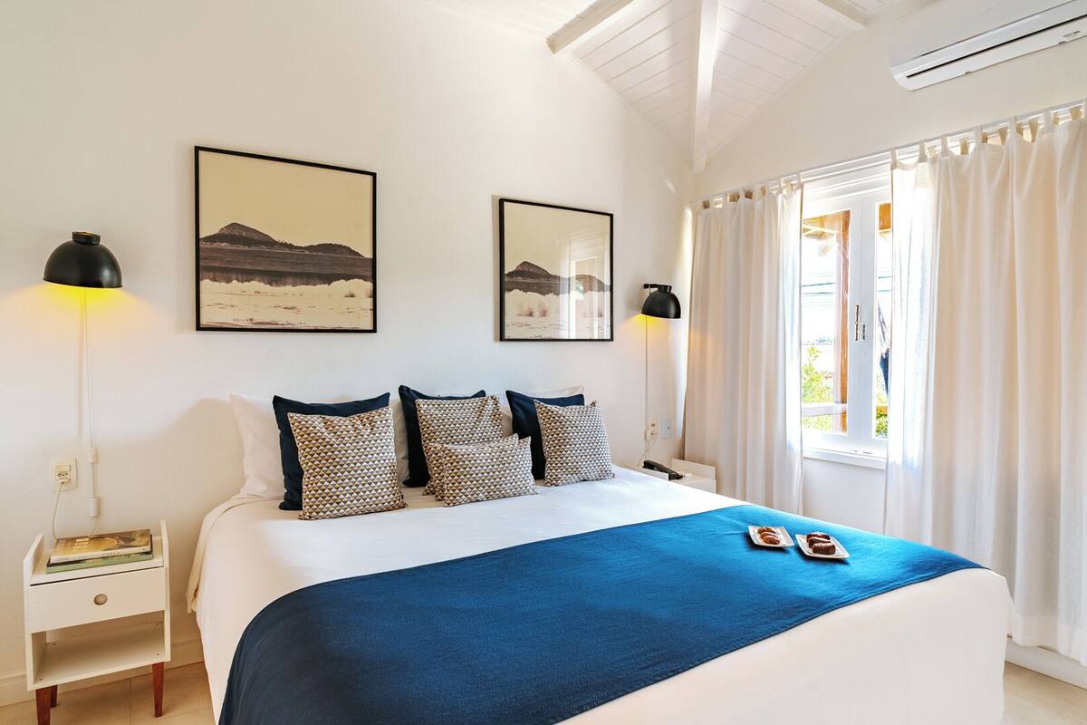 Un dormitorio con una cama grande, dos lámparas de noche, una mesita de noche y dos cuadros en la pared.