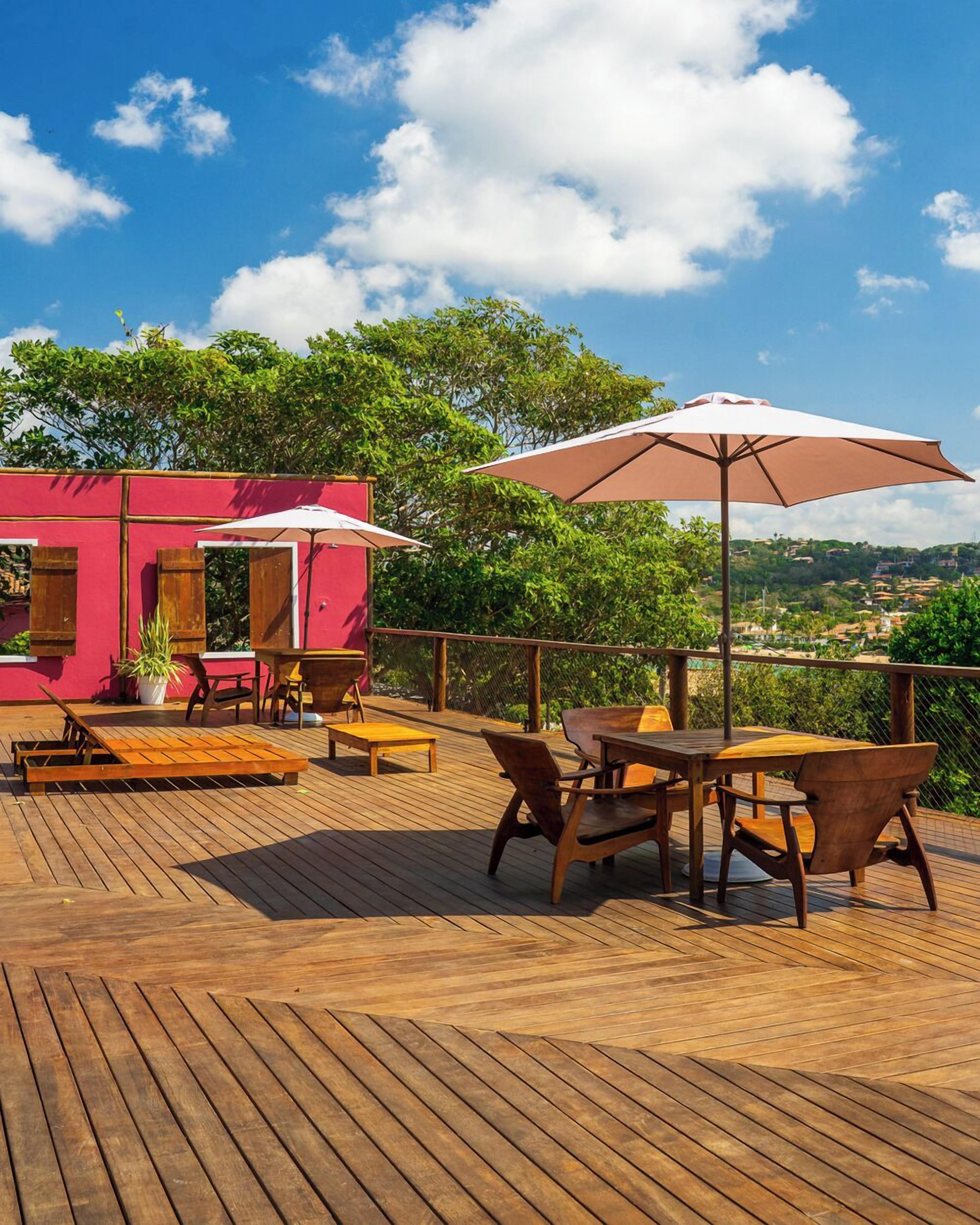 A wooden deck with outdoor furniture and a pink building in the background.