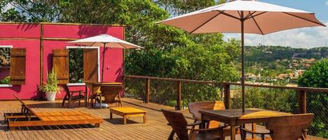 A wooden deck with outdoor furniture and a pink building in the background.