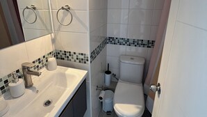 Un baño moderno con lavamanos blanco, inodoro y zona de ducha.