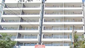 Un edificio de varios pisos con balcones, un letrero que indica una farmacia y líneas eléctricas visibles.