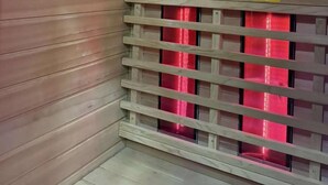 Interior de un ascensor con paneles de madera, una pantalla digital y un letrero de salida de emergencia rojo.