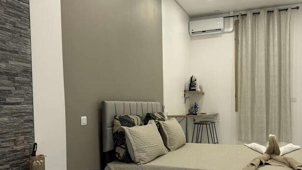 Un dormitorio moderno con una cama grande, una mesita de noche, un equipo de aire acondicionado y una bañera.