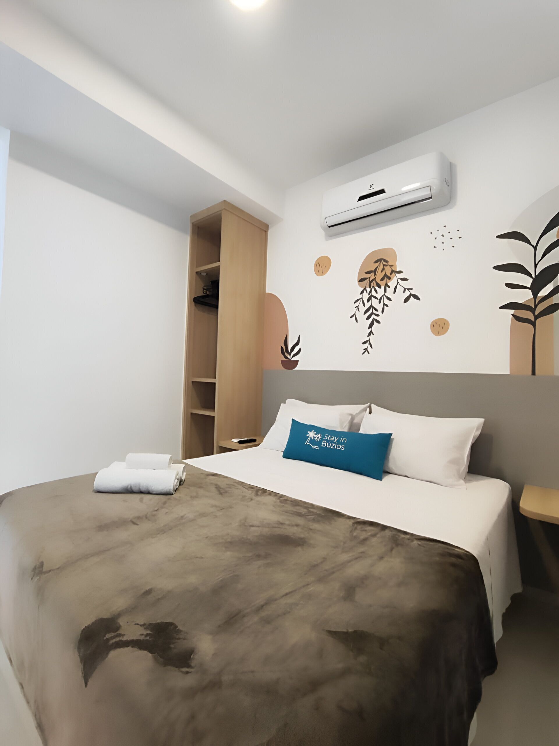 Camera d'albergo moderna con un letto, un armadio, un condizionatore e opere d'arte a parete.