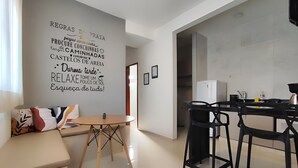 A modern living room with a sofa, a round table, and black chairs. A wall with motivational text is visible. - Búzios Suíte Home (Búzios)