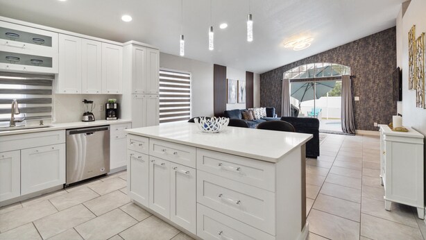 A modern kitchen with white cabinetry, a dishwasher, and a central island. - Fascinating private pool and game-room, near Disney!! (Kissimmee)