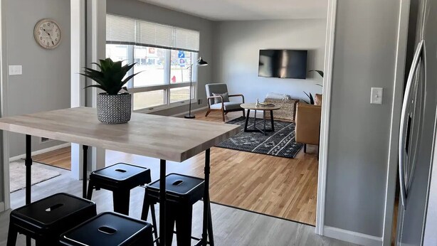 Una cocina moderna con una mesa de madera, taburetes negros y una planta en maceta.