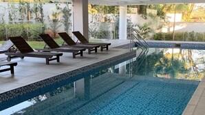 An indoor swimming pool with tiled flooring and lounge chairs. - Flat Vip 5 Estrelas (Cotia)