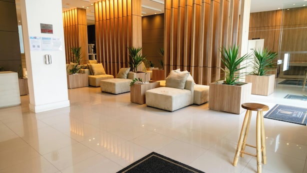 A modern lobby with a seating area, wooden accents, and potted plants. - Flat Vip 5 Estrelas (Cotia)
