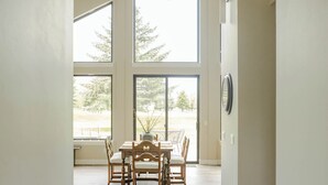 A spacious room with a high ceiling, large windows, and a dining area with a chandelier. - NEW charming 3 bedroom cottage nestled on the scenic Red Lodge Golf Course  (Red Lodge)