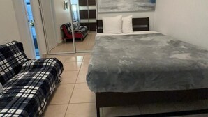 Une chambre moderne avec un lit, un canapé et une porte coulissante donnant sur une salle de bain.