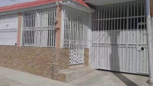 Une maison avec une entrée fermée par un portail, une véranda et un toit en tuiles.