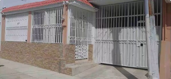 Une maison avec une entrée fermée par un portail, une véranda et un toit en tuiles.