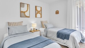 Un dormitorio con dos camas, una mesita de noche con lámpara y un espejo instalado en la pared.