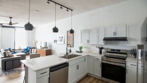 A modern kitchen with white cabinets, a dishwasher, an oven, and pendant lights. - Cozy studio in enchanting downtown Warrensburg with full kitchen, AC, WiFi (Warrensburg)