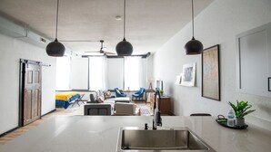 A modern kitchen with a built-in dishwasher, a large island with a sink, and pendant lighting. - Cozy studio in enchanting downtown Warrensburg with full kitchen, AC, WiFi (Warrensburg)