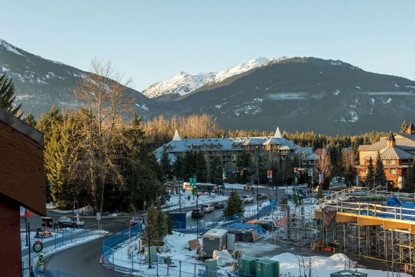 A mountain resort with a large building in the center, surrounded by snow-covered mountains and trees.