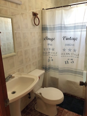 A bathroom with a toilet, sink, and shower curtain. - Detached, fully furnished cabin with a patio and grill, just a few steps from Playa Negra (Concón)
