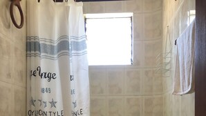 A bathroom with a toilet, sink, and bathtub. A shower curtain with text is hanging above the bathtub. - Detached, fully furnished cabin with a terrace and barbecue, just steps from Playa Negra, (Concón)