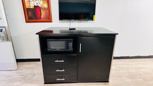 A black desk with a microwave, a flat-screen TV, and a framed artwork on the wall. - Bryce Park Inn (Panguitch)