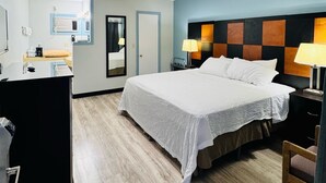 A hotel room with a bed, bedside lamps, a desk, and a mirror. - Bryce Park Inn (Panguitch)