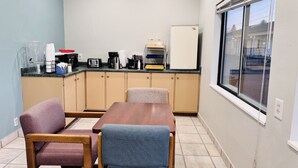 A small kitchenette with a refrigerator, coffee maker, and toaster. There are two chairs and a table in the room. - Bryce Park Inn (Panguitch)
