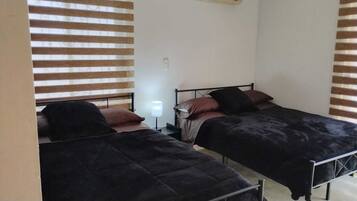 A room with two beds, each with a headboard and pillows, and a bedside table with a lamp.
